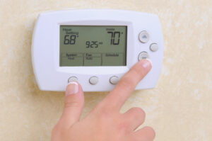 hand on thermostat changing the temperature