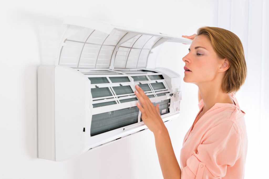 young woman opening wall mount air conditioner unit