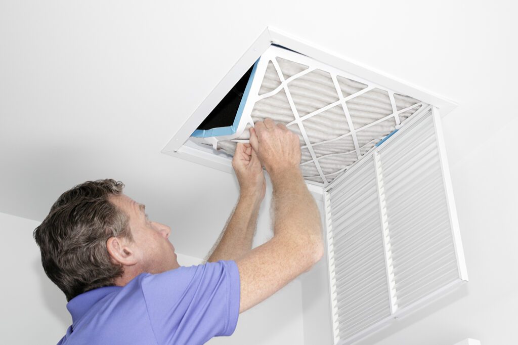 man on ladder changing air filter to improve air quality