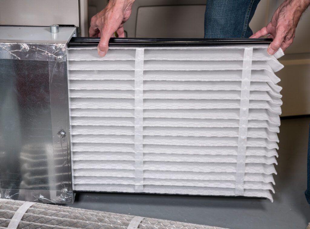 two hands installing new furnace filter