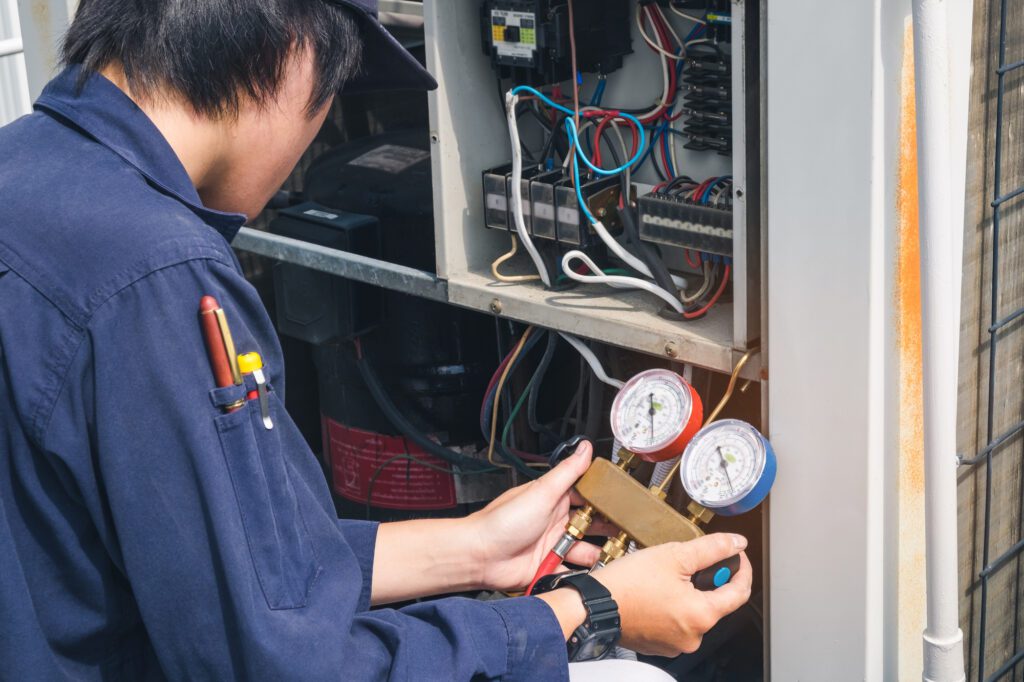 hvac contractor wearing blue performing routine maintenance on hvac unit